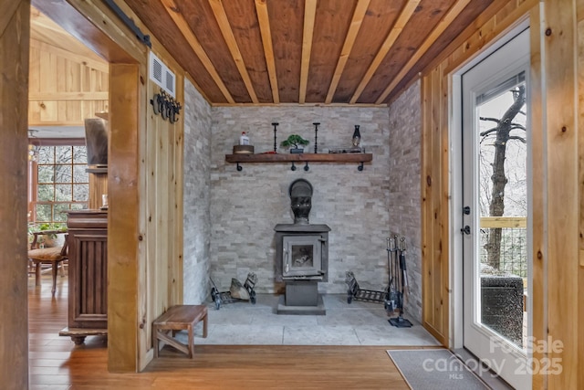 interior space featuring a wood stove, wooden ceiling, visible vents, and wood finished floors