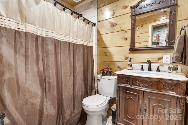 bathroom featuring a shower with shower curtain, wooden walls, toilet, and vanity