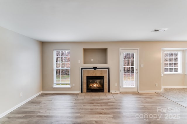 unfurnished living room featuring light wood-type flooring, baseboards, a fireplace, and visible vents