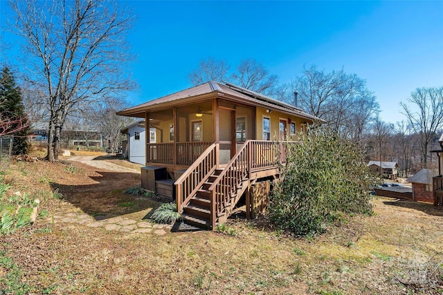 view of front of home with a wooden deck, stairway, solar panels, and metal roof