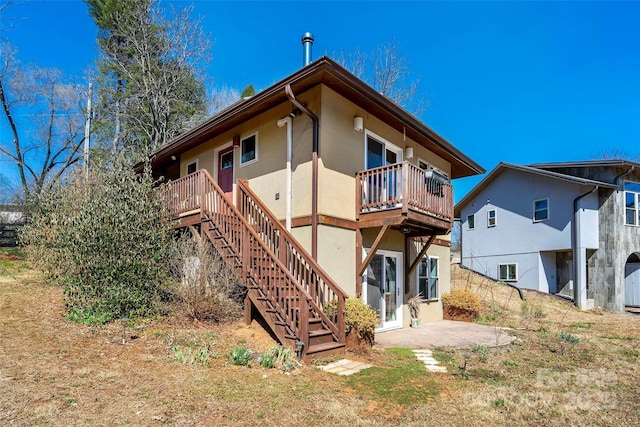 rear view of house with a patio, stairway, and stucco siding