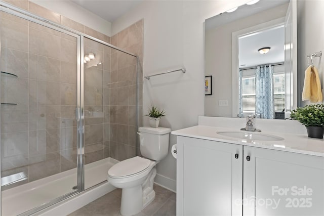 full bath featuring toilet, a shower stall, vanity, baseboards, and tile patterned floors