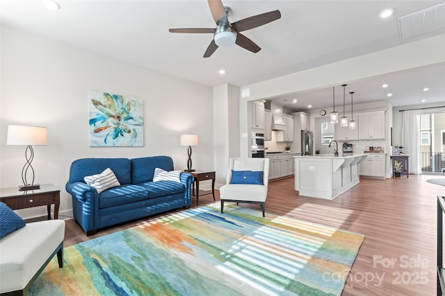 living area featuring light wood finished floors, visible vents, and recessed lighting