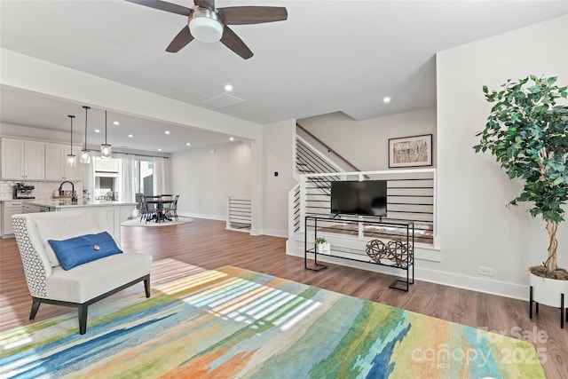 living area featuring stairs, baseboards, wood finished floors, and recessed lighting