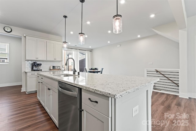 kitchen with decorative light fixtures, a sink, a center island with sink, and white cabinets