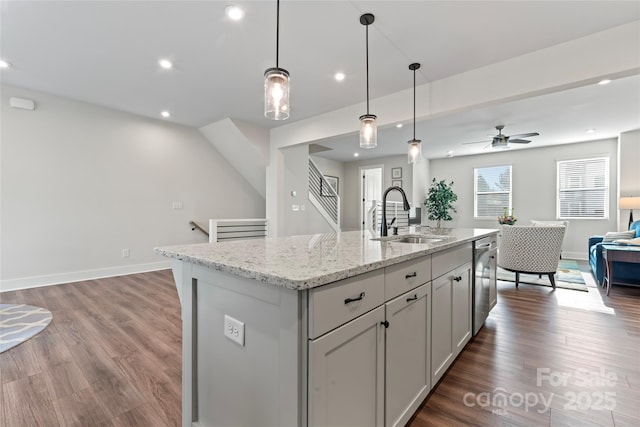 kitchen with pendant lighting, a kitchen island with sink, a sink, and stainless steel dishwasher