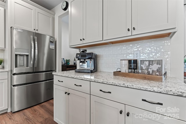 kitchen featuring tasteful backsplash, white cabinets, dark wood finished floors, light stone countertops, and stainless steel refrigerator with ice dispenser