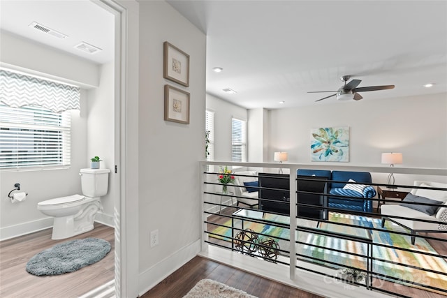 hallway featuring visible vents, baseboards, and wood finished floors