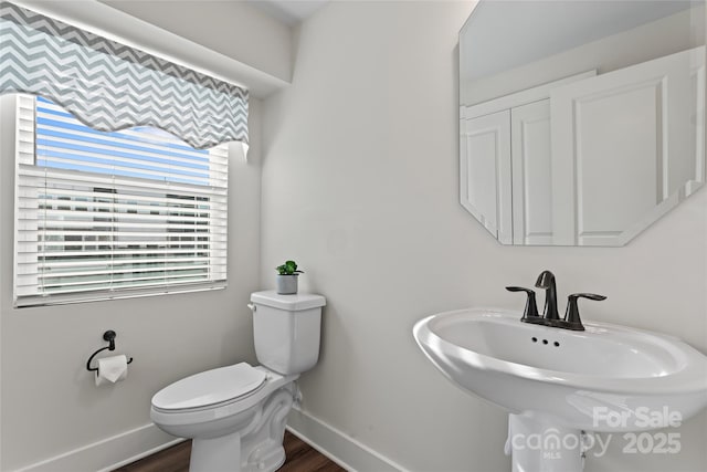 bathroom with baseboards, a sink, toilet, and wood finished floors