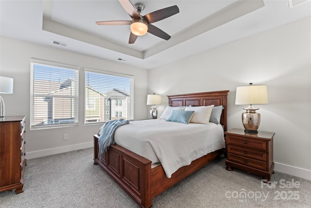 bedroom with light colored carpet, visible vents, a ceiling fan, baseboards, and a raised ceiling