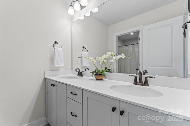 full bathroom with double vanity, baseboards, and a sink