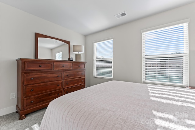 bedroom with baseboards, visible vents, and light colored carpet