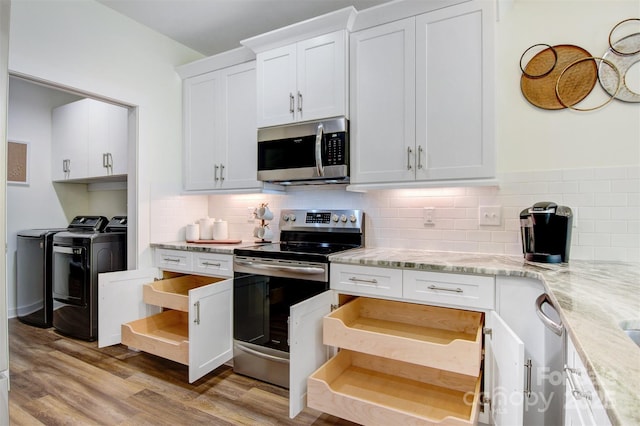 kitchen with light wood finished floors, stainless steel appliances, backsplash, white cabinets, and separate washer and dryer