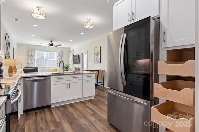 kitchen with appliances with stainless steel finishes, open floor plan, dark wood-type flooring, white cabinetry, and a sink