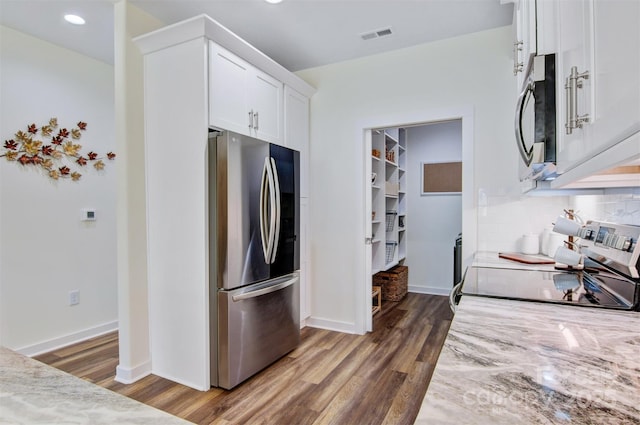 kitchen featuring stainless steel appliances, dark wood-style flooring, visible vents, white cabinets, and light stone countertops