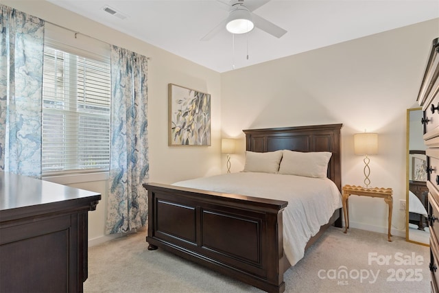 bedroom with light carpet, ceiling fan, visible vents, and baseboards