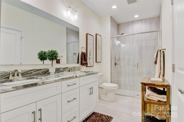 bathroom with toilet, a stall shower, and a sink