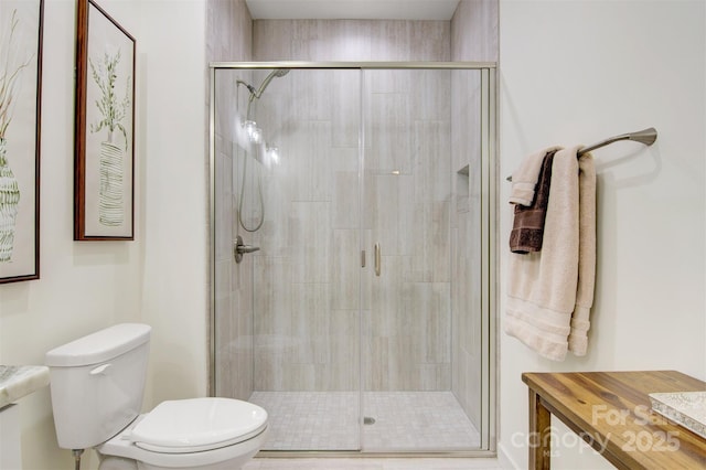 bathroom with vanity, a shower stall, and toilet