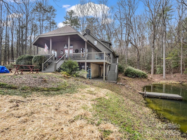 back of property with a shingled roof, stairs, and a wooden deck