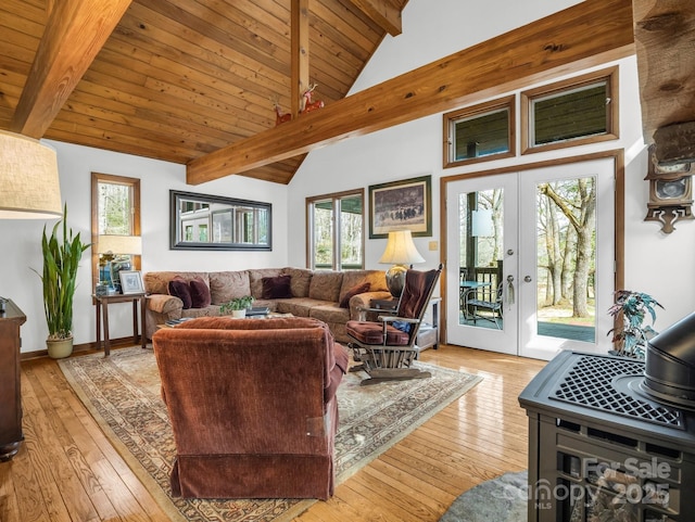 living room with a wood stove, french doors, light wood-style flooring, and beam ceiling