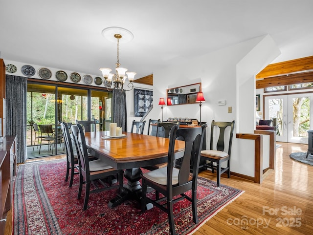 dining space featuring light wood finished floors, french doors, a wealth of natural light, and a notable chandelier