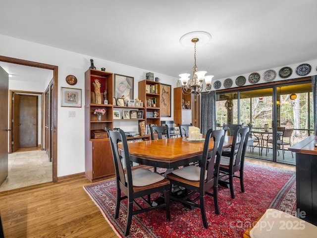 dining area with baseboards, light wood finished floors, and an inviting chandelier