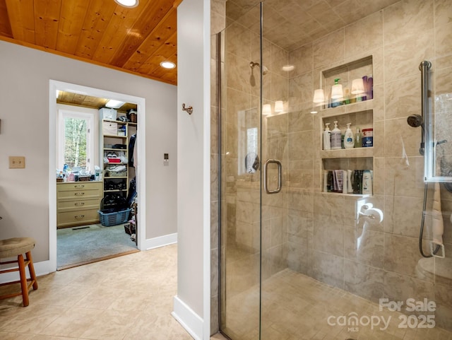 bathroom featuring wood ceiling, a shower stall, a spacious closet, and baseboards