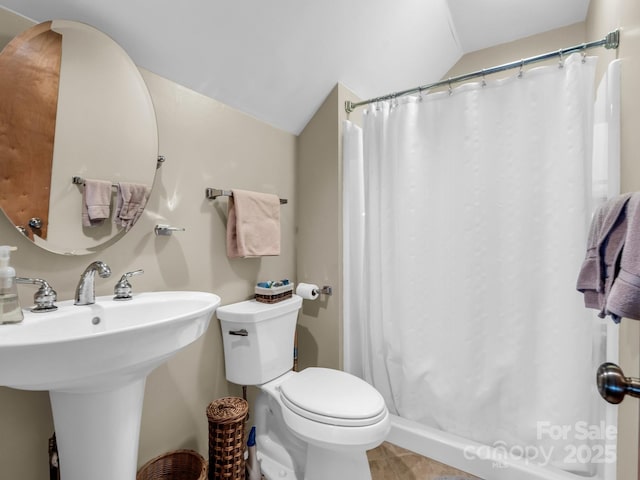 full bath with a shower with shower curtain, toilet, a sink, vaulted ceiling, and tile patterned floors