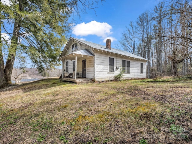 view of front of property with a front lawn, a chimney, and a porch