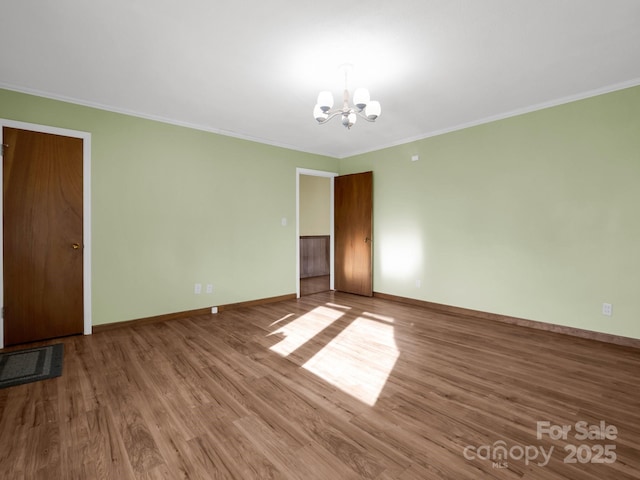 empty room featuring ornamental molding, an inviting chandelier, and wood-type flooring