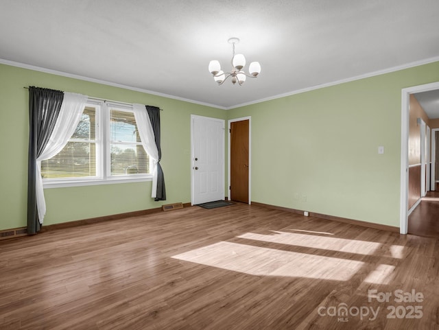 empty room with light hardwood / wood-style flooring, crown molding, and an inviting chandelier