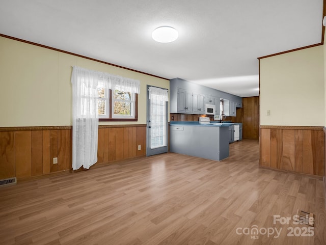 kitchen featuring light hardwood / wood-style flooring, sink, wood walls, and kitchen peninsula