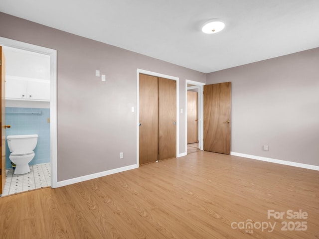 unfurnished bedroom featuring light hardwood / wood-style floors and ensuite bath