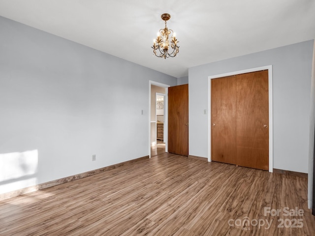 unfurnished bedroom with light hardwood / wood-style flooring, an inviting chandelier, and a closet