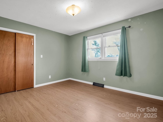 unfurnished bedroom featuring light wood-type flooring and a closet