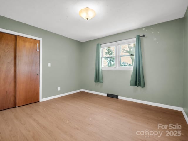 unfurnished bedroom with light wood-type flooring and a closet