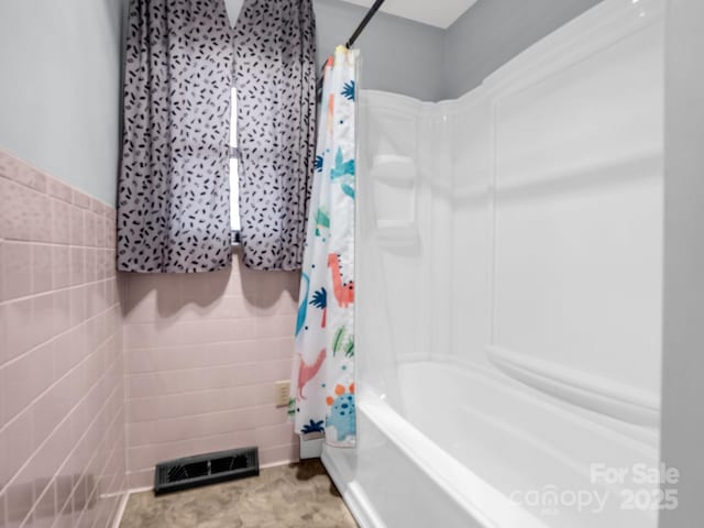 bathroom featuring tile walls and shower / bath combination with curtain