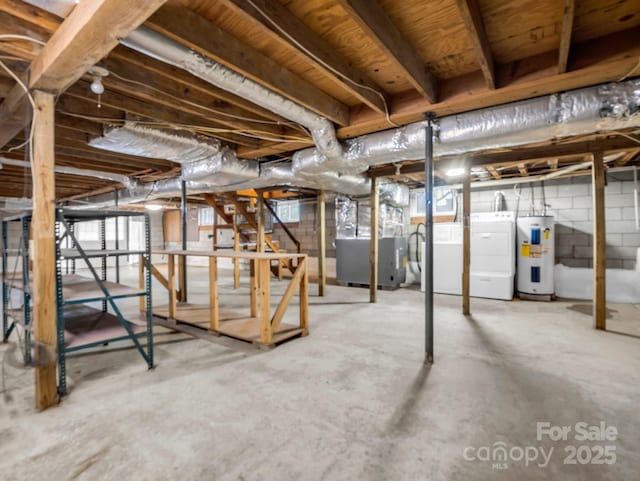 basement featuring heating unit, electric water heater, and washer and clothes dryer