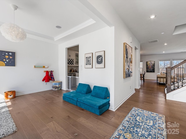 living area with a tray ceiling, visible vents, dark wood-type flooring, baseboards, and stairs