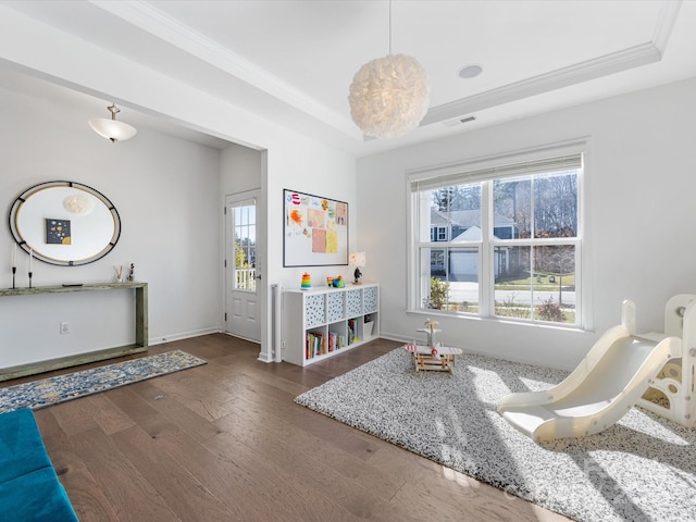 interior space featuring baseboards, visible vents, dark wood finished floors, a tray ceiling, and crown molding