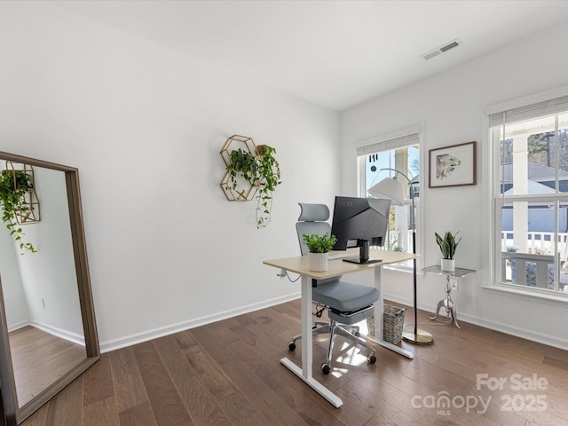 office space with dark wood-style flooring, plenty of natural light, visible vents, and baseboards