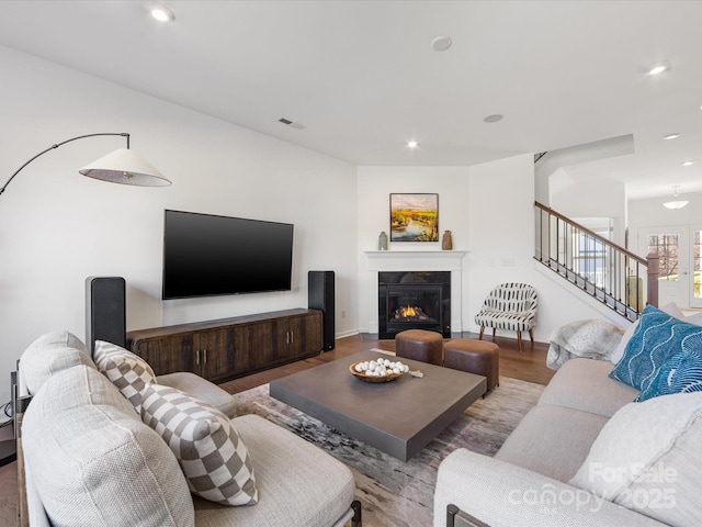 living room featuring light wood finished floors, visible vents, a glass covered fireplace, stairs, and recessed lighting