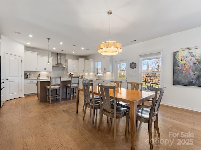 dining area featuring baseboards, light wood finished floors, and recessed lighting