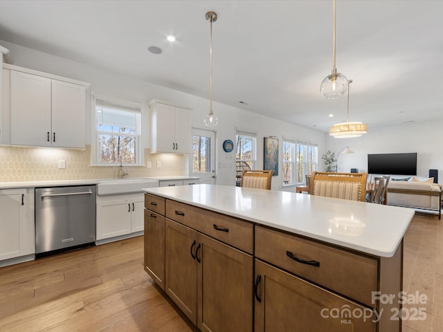 kitchen featuring light countertops, stainless steel dishwasher, white cabinetry, and brown cabinets