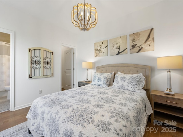 bedroom with connected bathroom, dark wood-style flooring, a notable chandelier, and baseboards