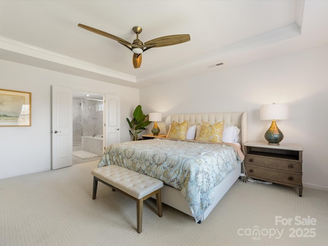 bedroom featuring baseboards, a tray ceiling, ensuite bath, and light colored carpet