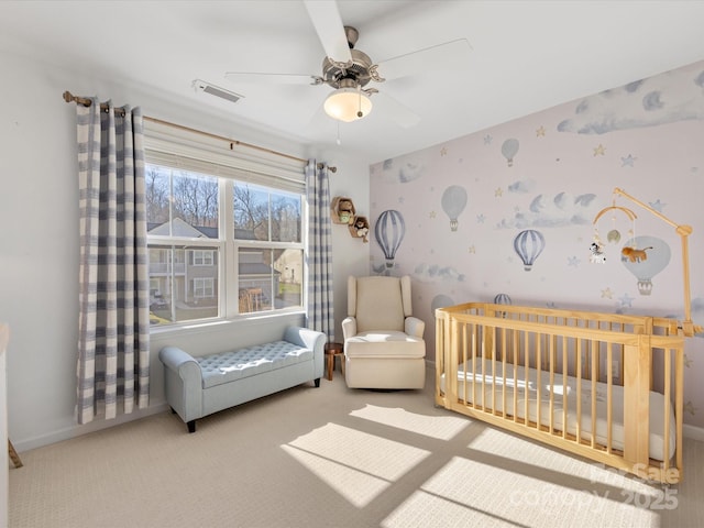 bedroom featuring a ceiling fan, visible vents, a nursery area, carpet, and wallpapered walls