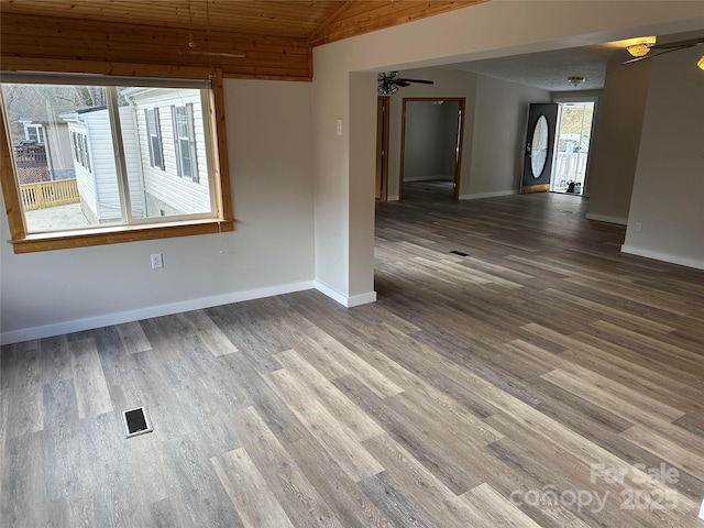 empty room with baseboards, visible vents, a ceiling fan, lofted ceiling, and wood finished floors