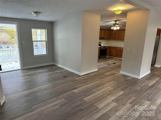 interior space with electric stove, brown cabinets, dark wood-type flooring, a textured ceiling, and baseboards