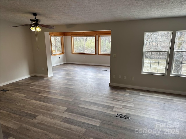 spare room with visible vents, a textured ceiling, baseboards, and wood finished floors